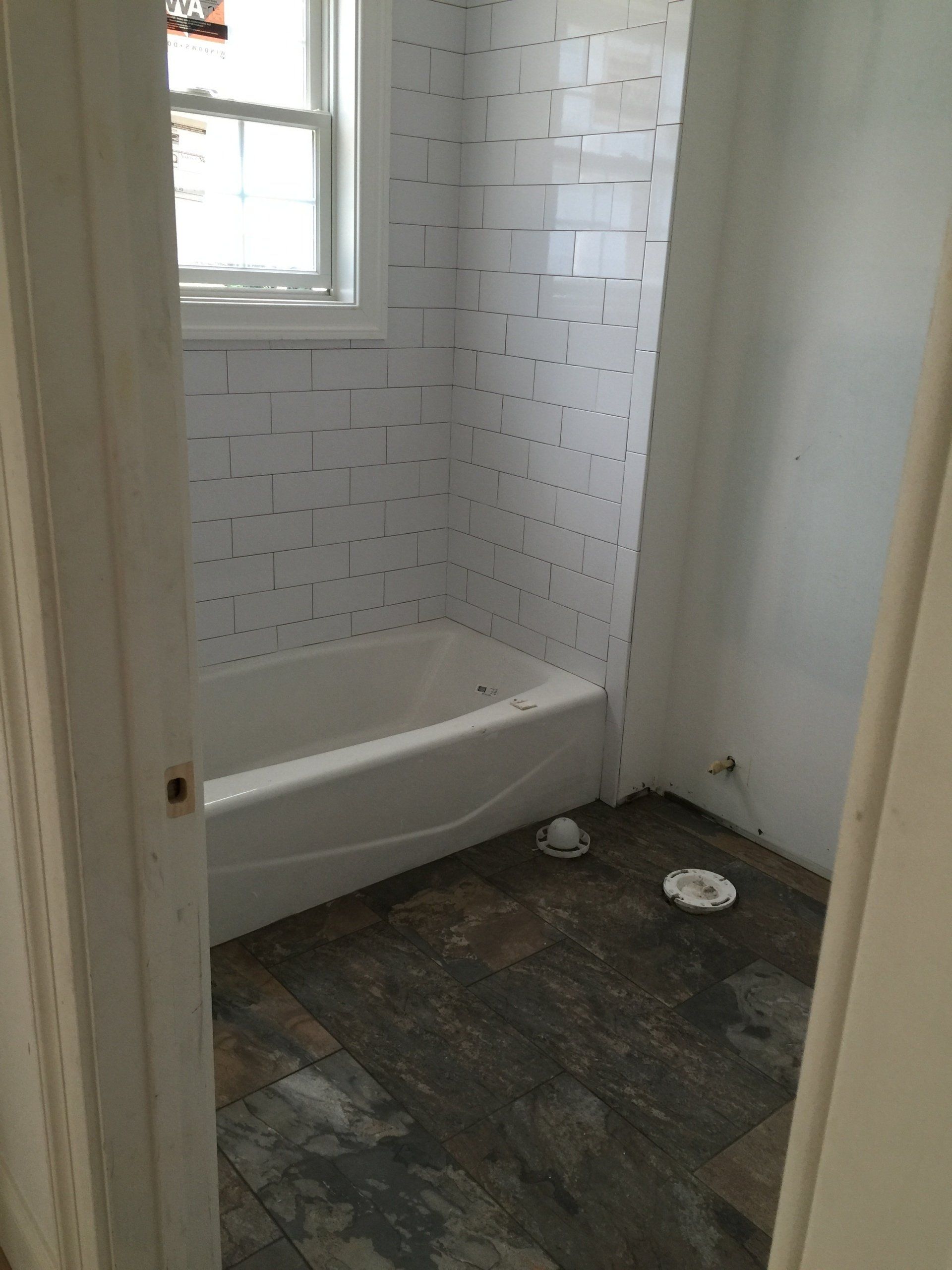 A bathroom with a bathtub and a window.