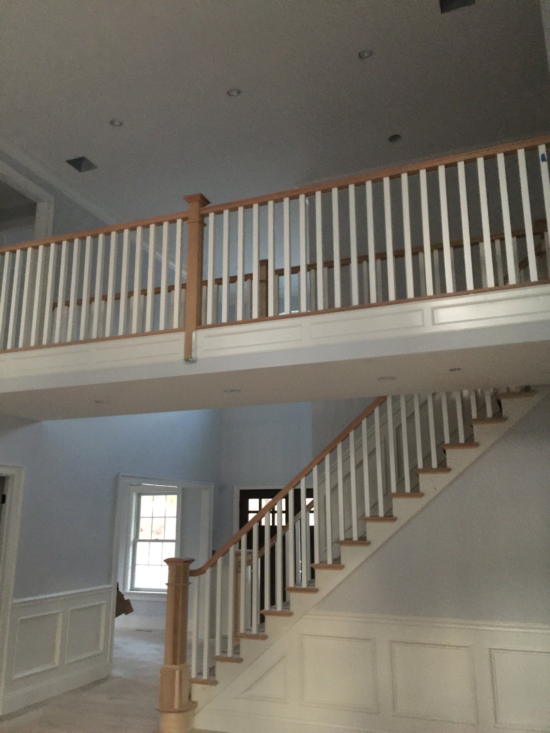 A staircase with white railings and a balcony above it