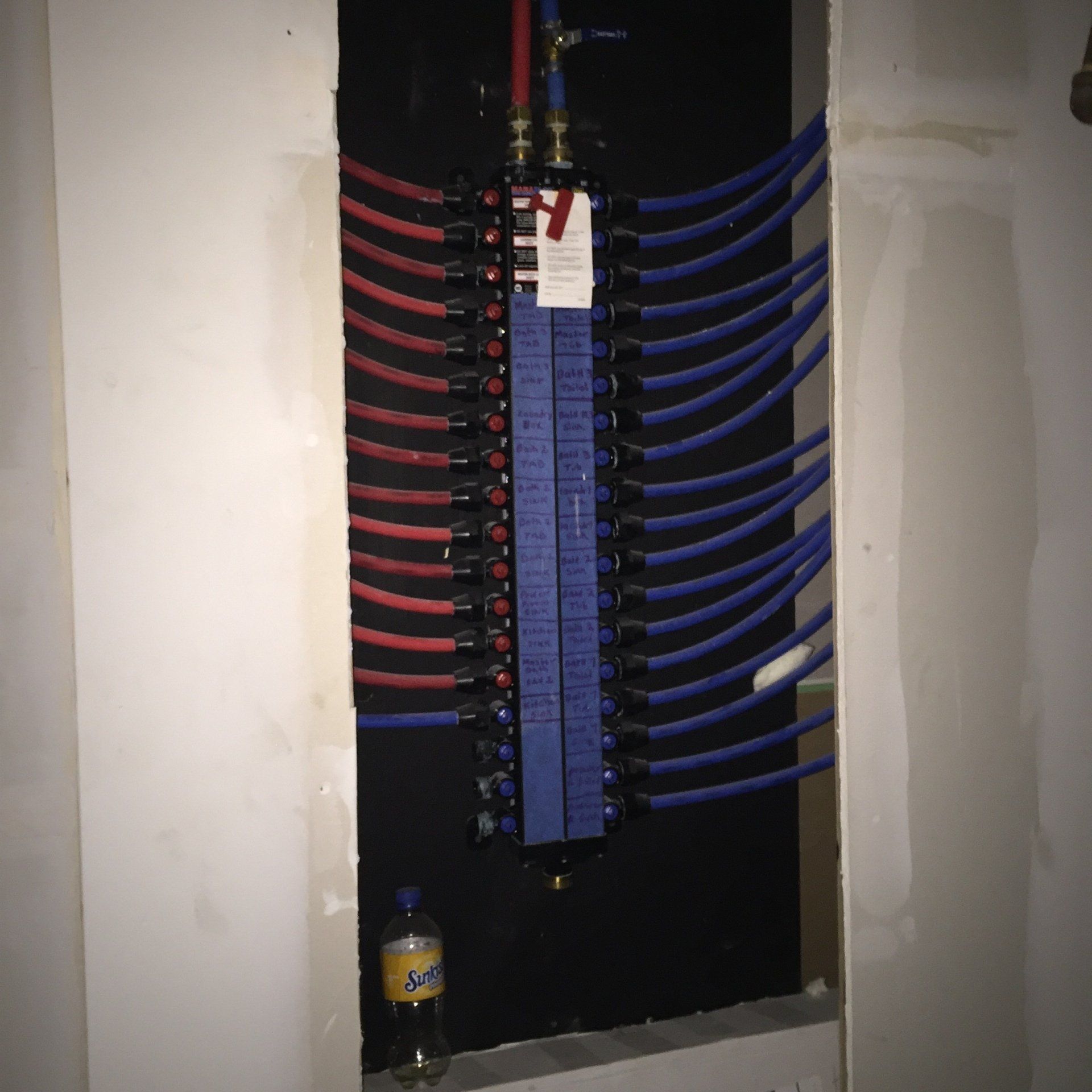 A bottle of coca cola sits next to an electrical box