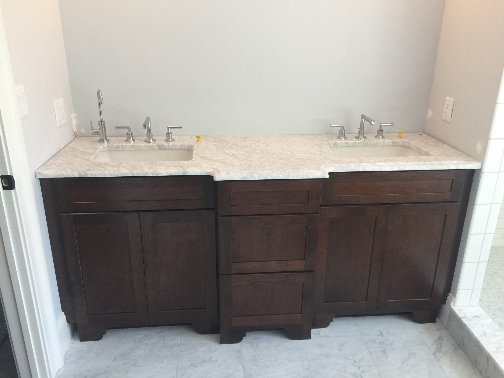A bathroom with two sinks and two cabinets.