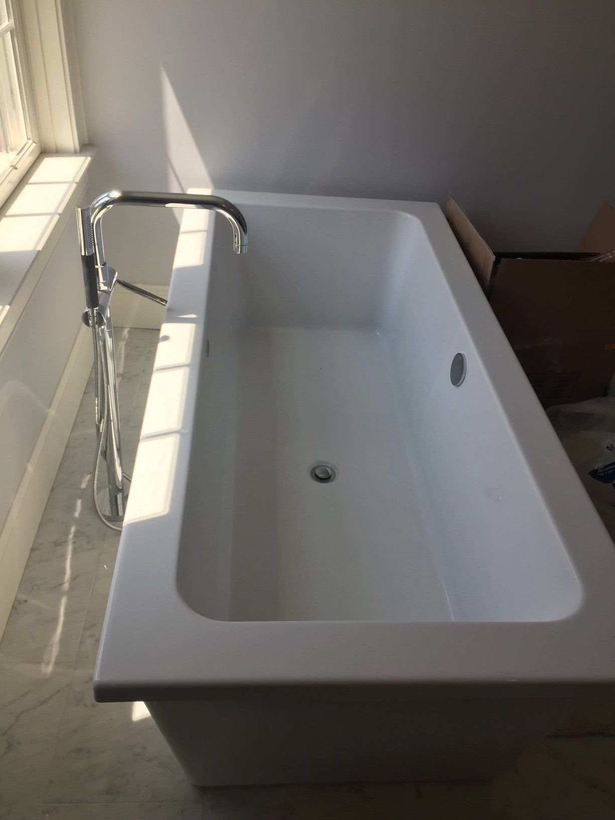 A white bathtub is sitting in a bathroom next to a window.