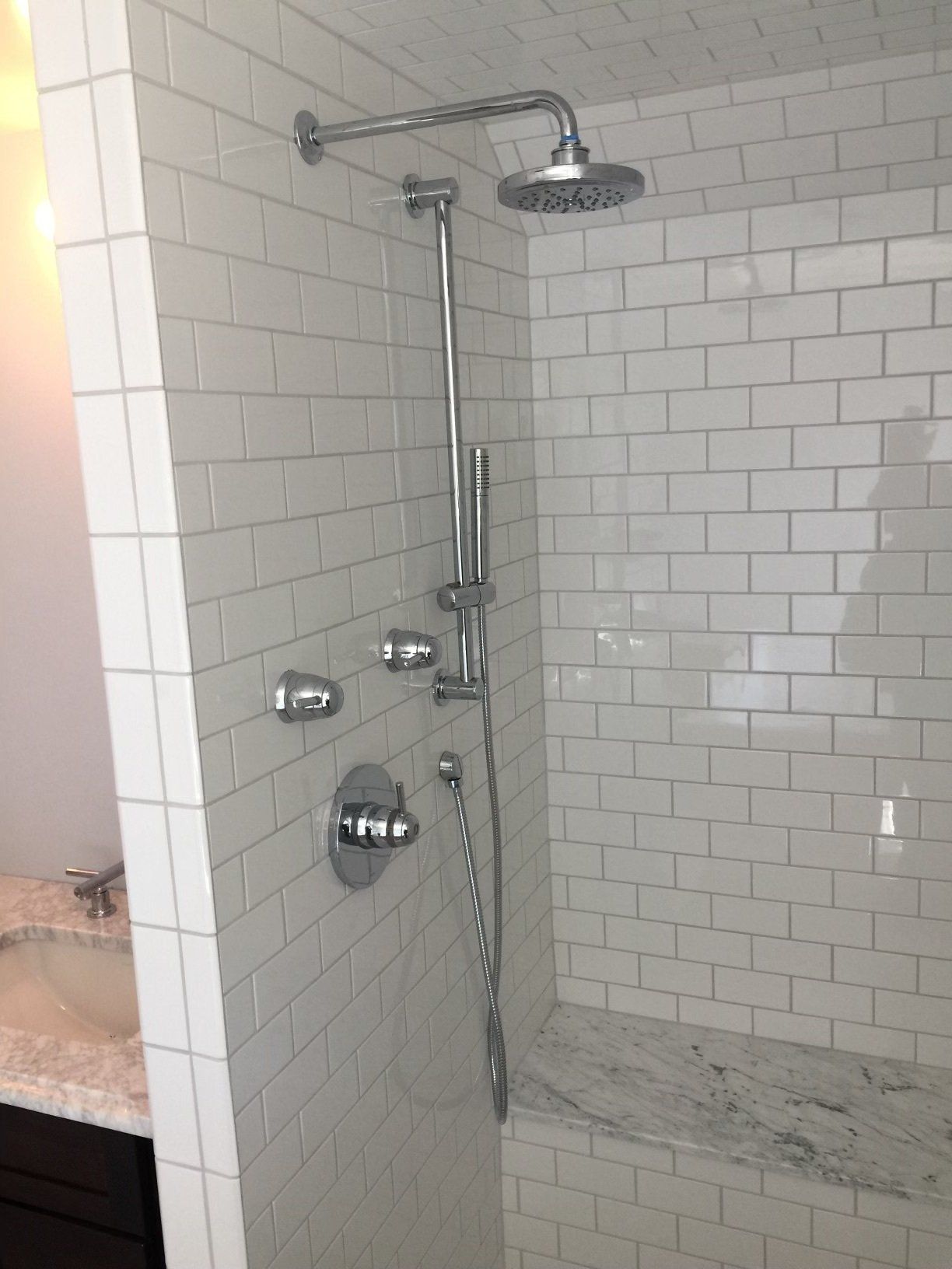 A bathroom with white tiles and a shower head