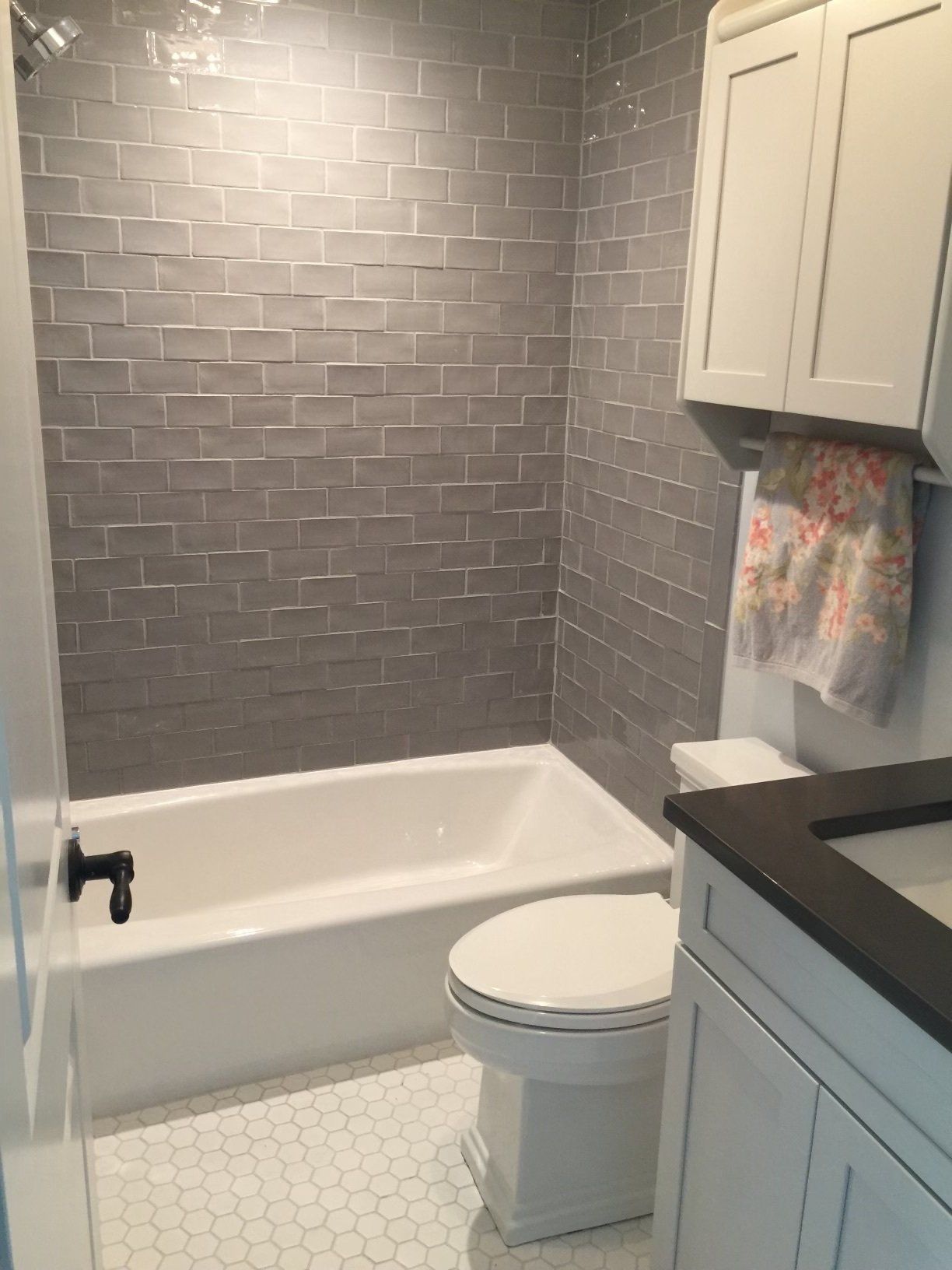 A bathroom with a toilet , tub , sink and cabinets.