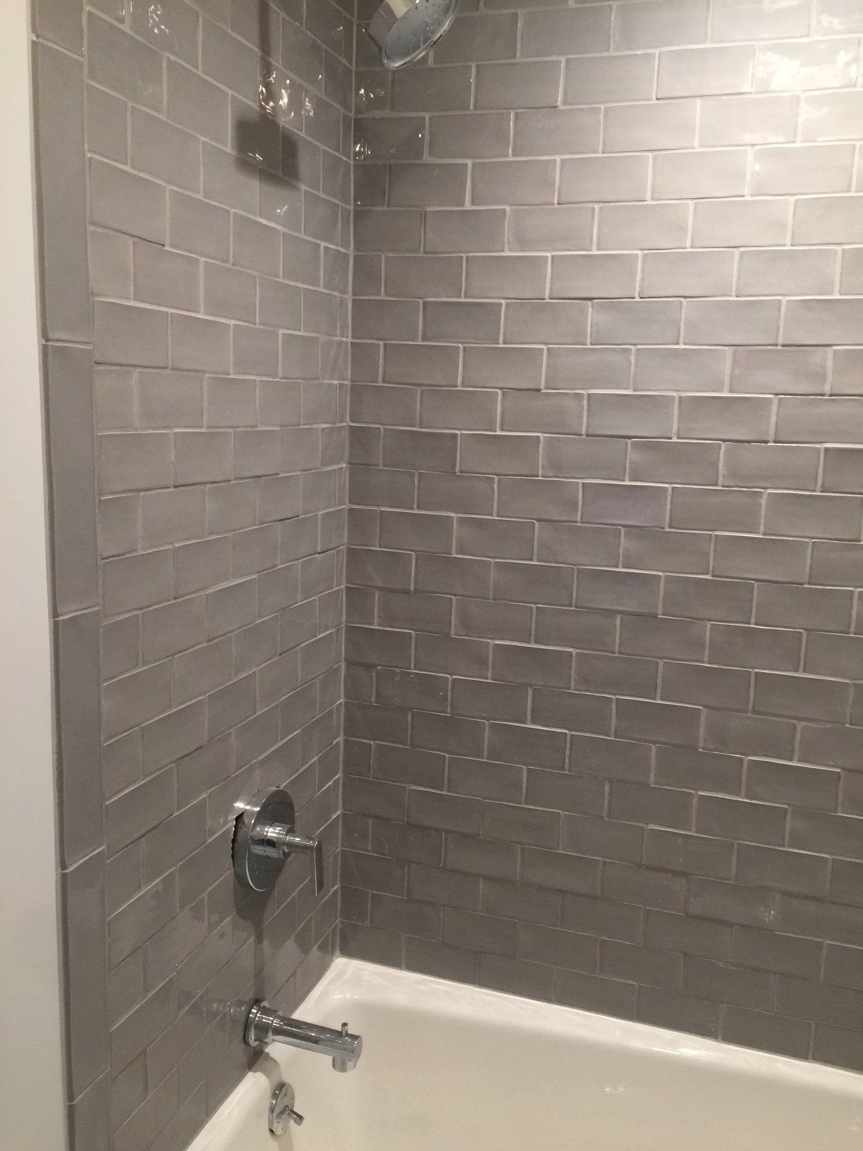 A bathroom with a bathtub and a shower with gray tiles.