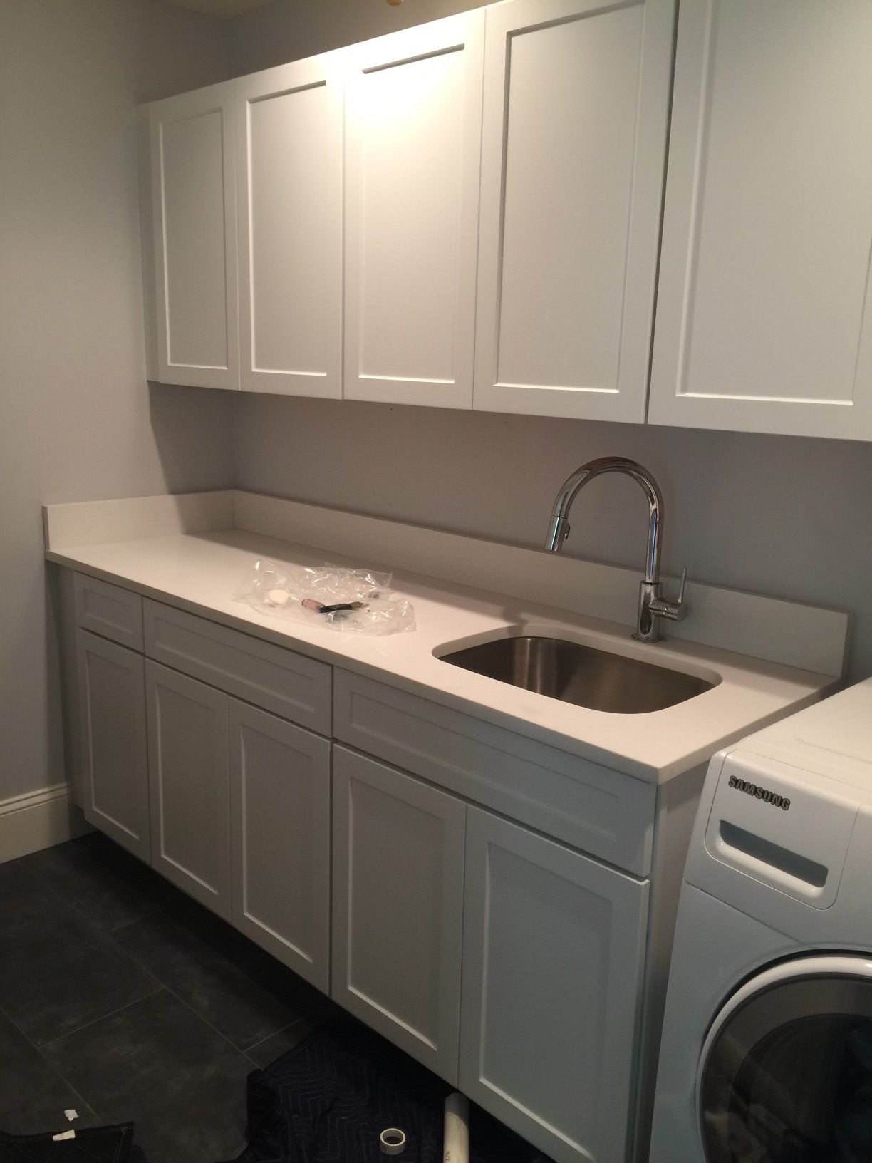 A laundry room with white cabinets and a sink