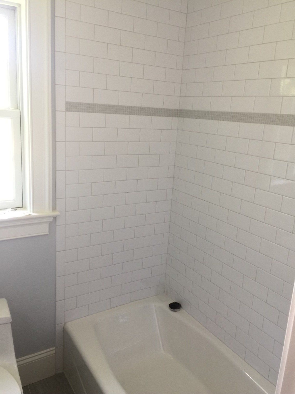 A bathroom with white subway tile walls and a bathtub.