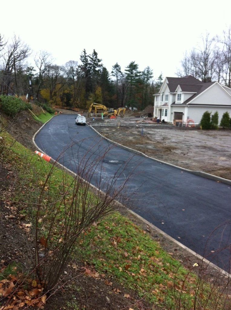 A car is driving down a curvy road in front of a house.