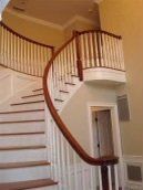 A curved staircase with a wooden railing in a house.