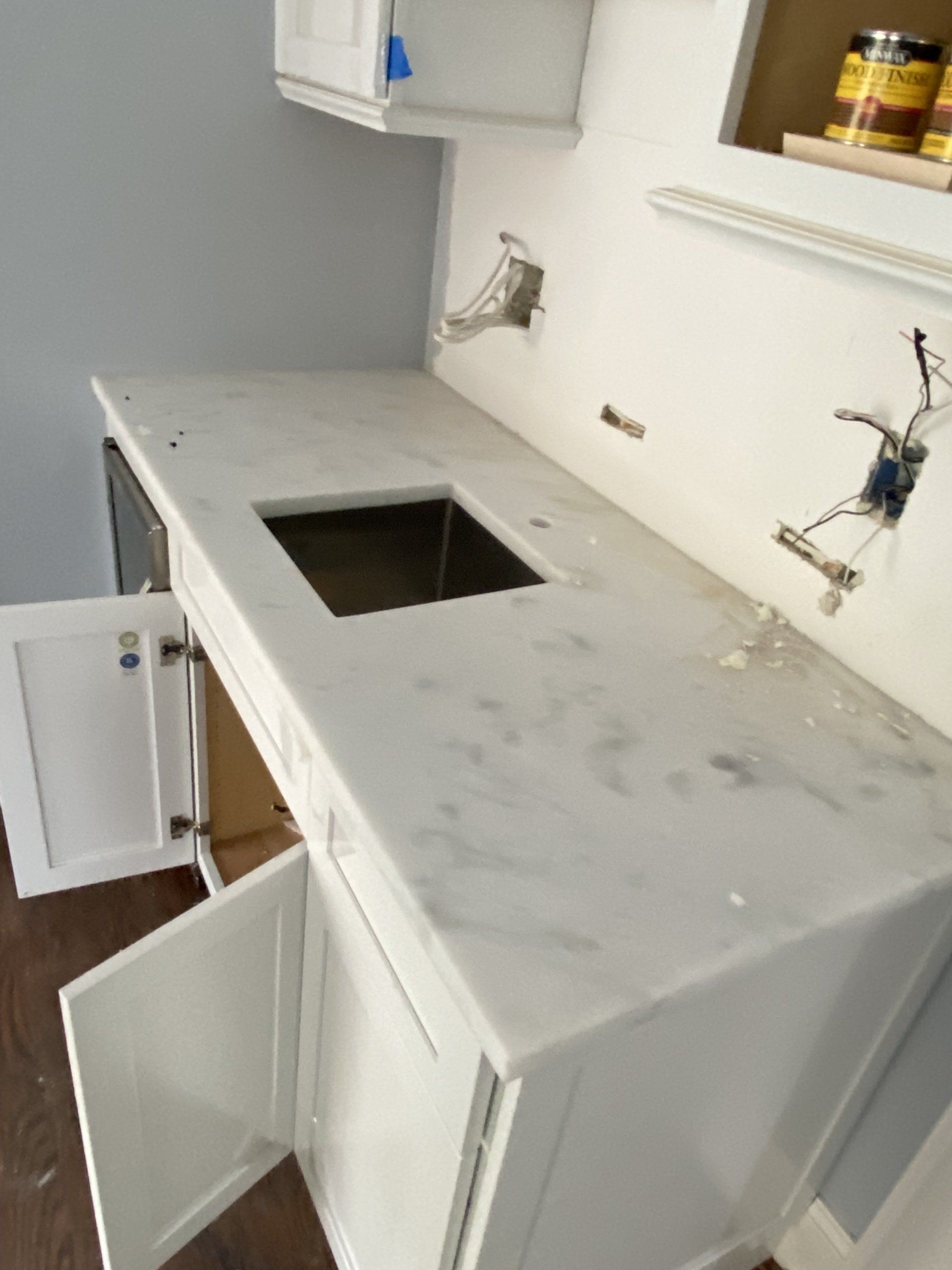 A kitchen with white cabinets and marble counter tops