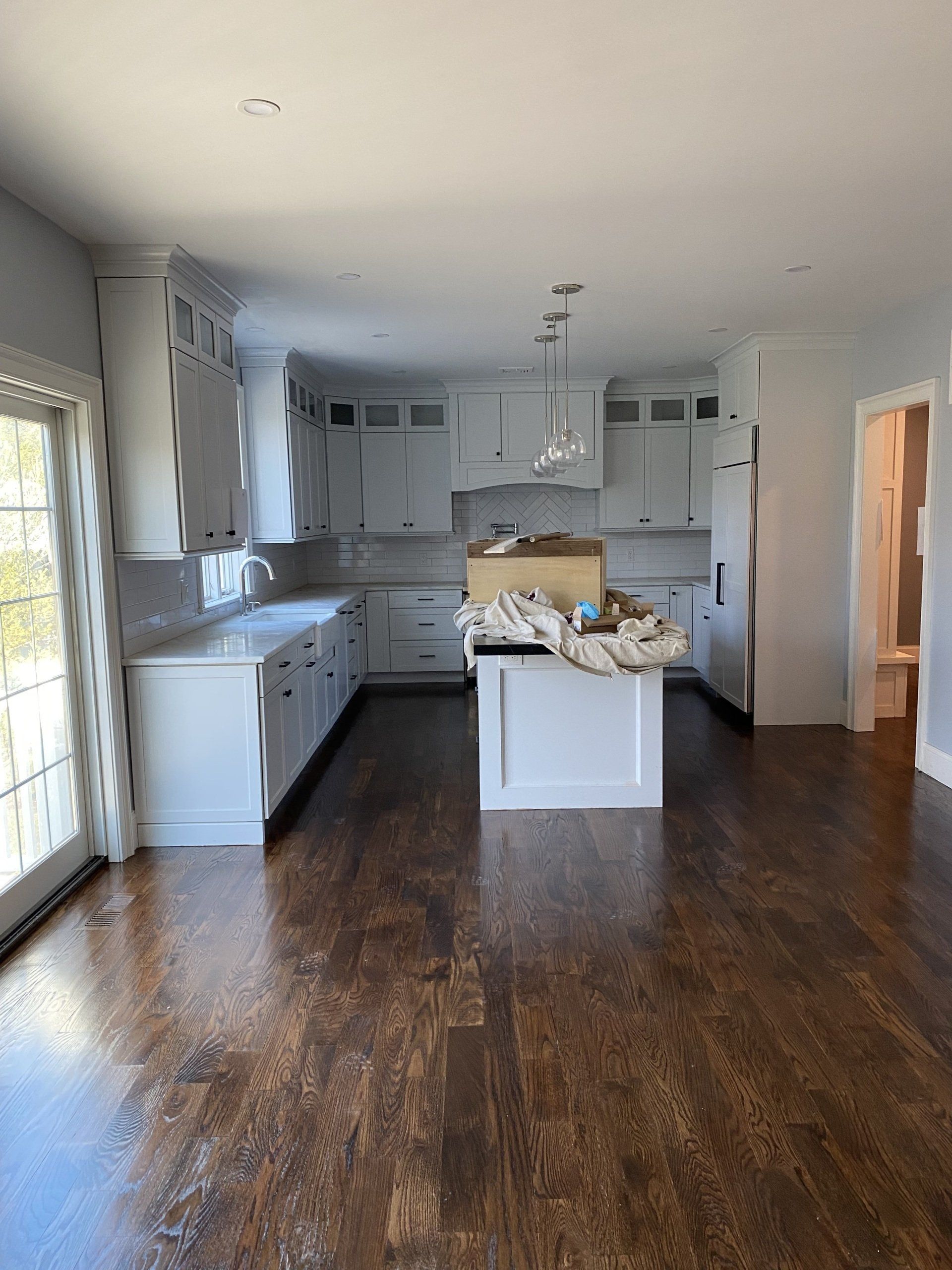 An empty kitchen with white cabinets and wooden floors.