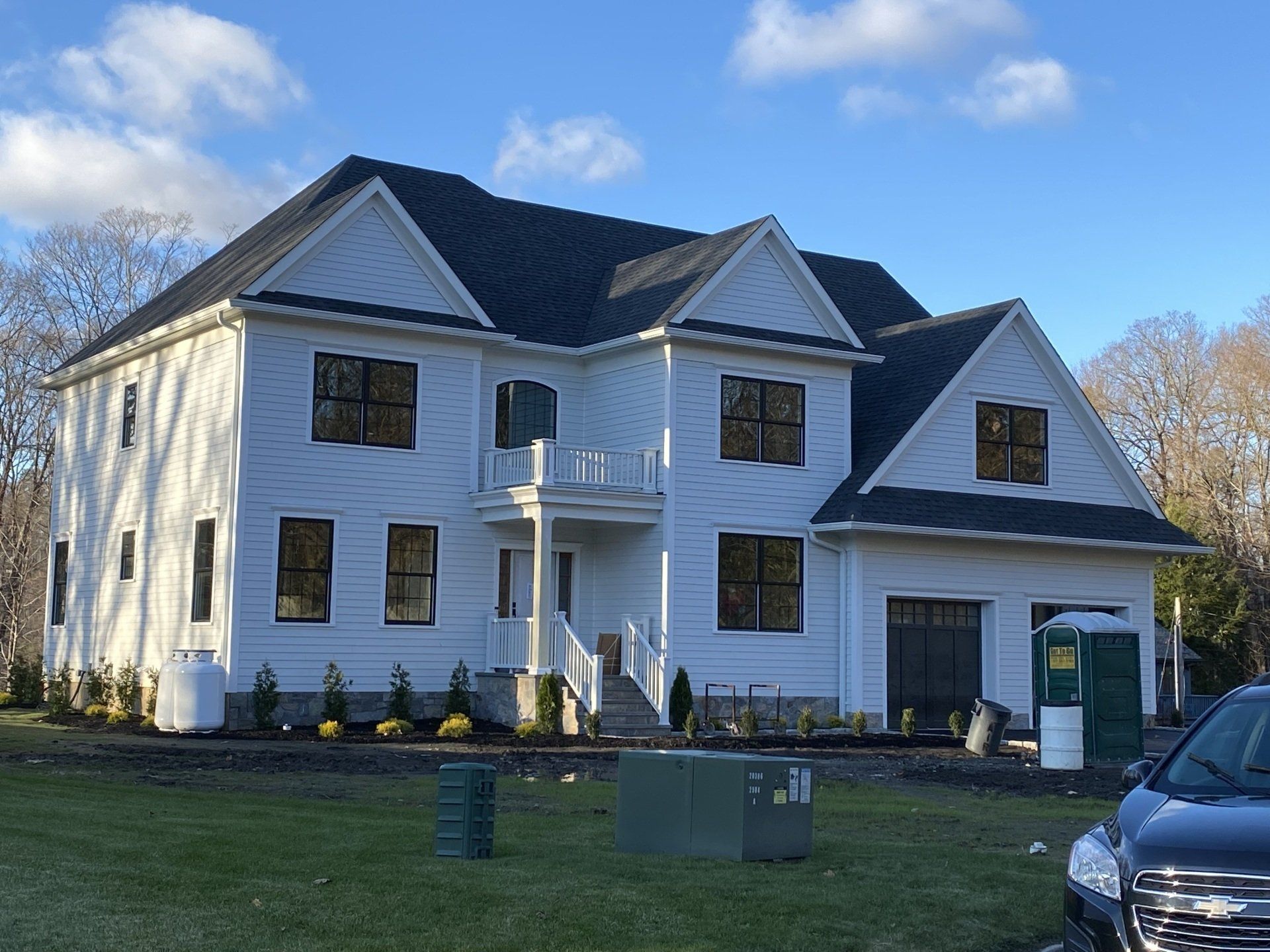 A large white house with a black roof is being built.