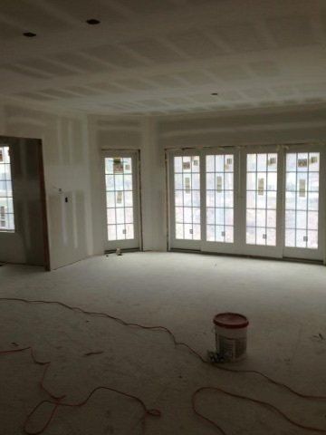 An empty room with lots of windows and a bucket on the floor