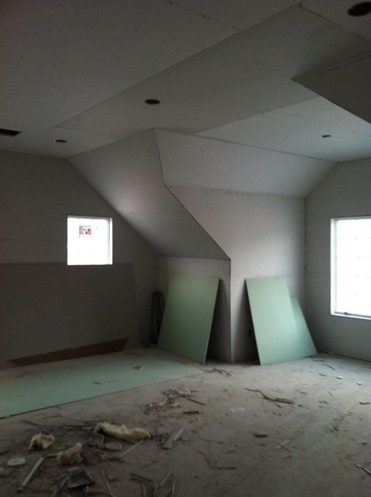 An empty room with a vaulted ceiling and two windows.