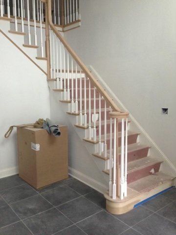 A wooden staircase with white railings is being built in a house.