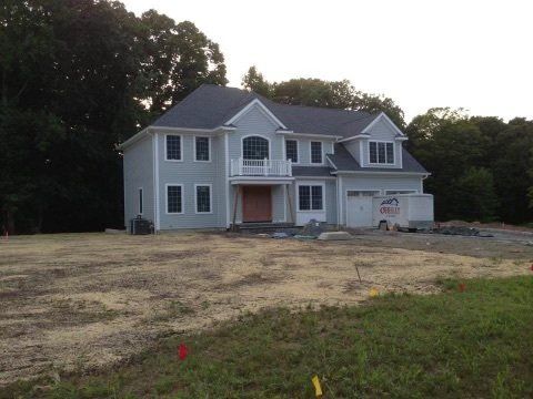 A large white house is sitting in the middle of a grassy field