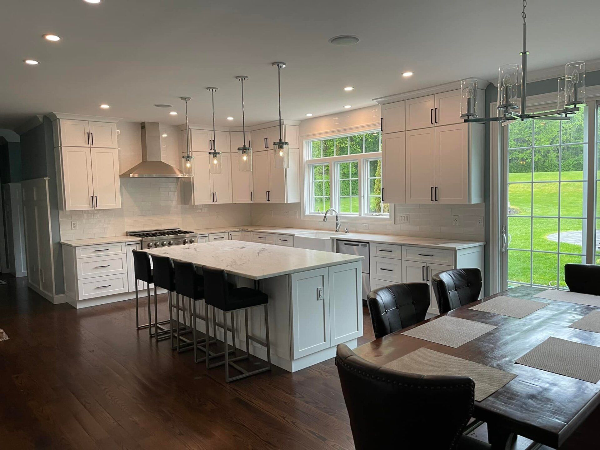 A kitchen with white cabinets , a large island , a table and chairs.