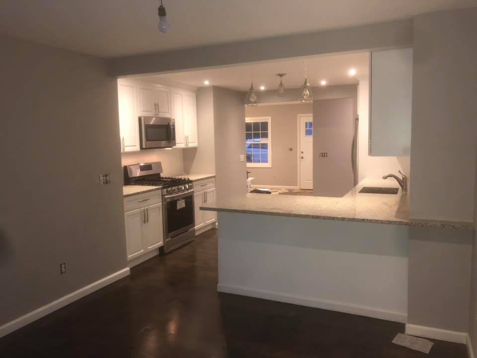 An empty kitchen with white cabinets and stainless steel appliances