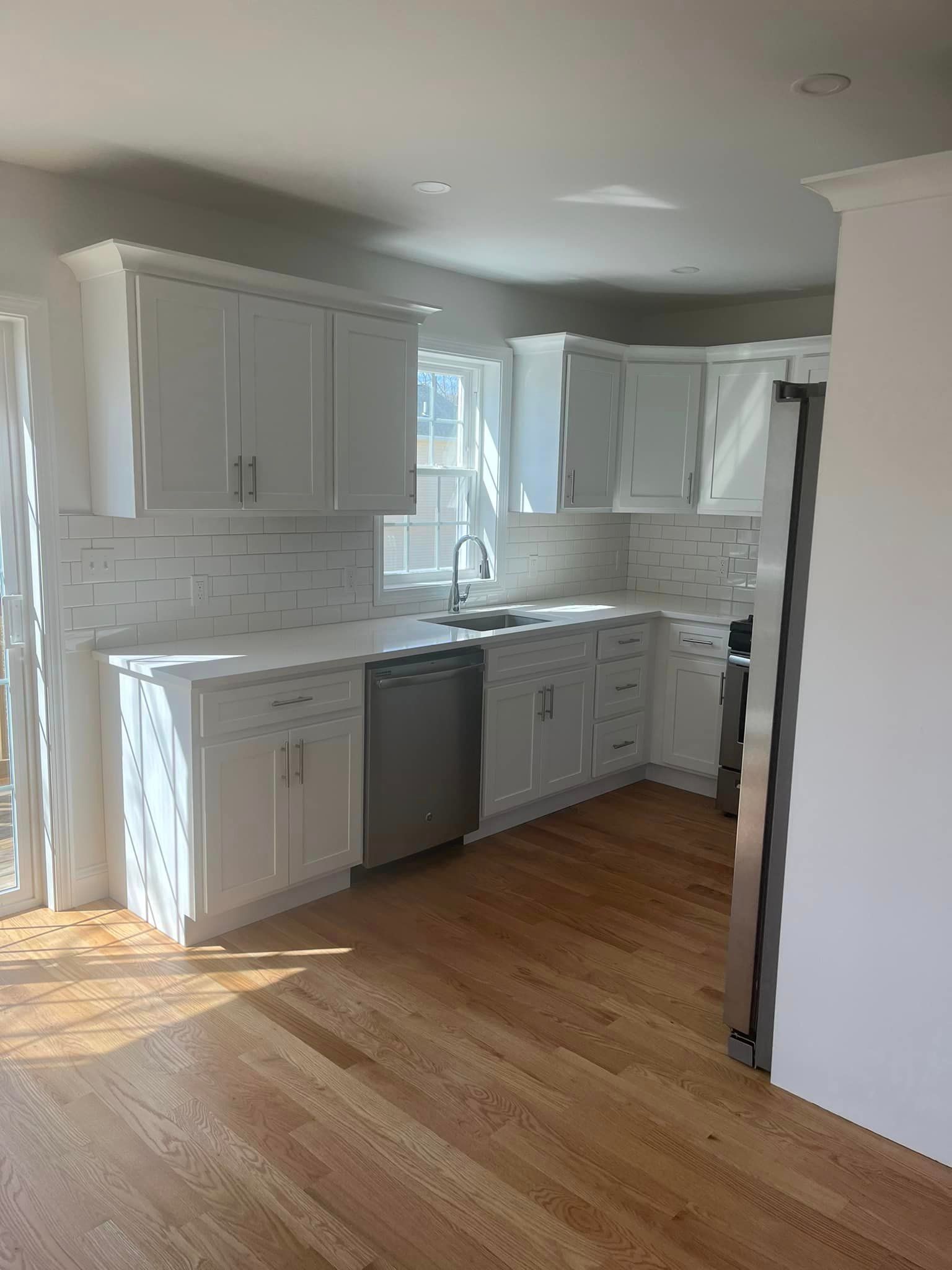 A kitchen with white cabinets , stainless steel appliances , and hardwood floors.