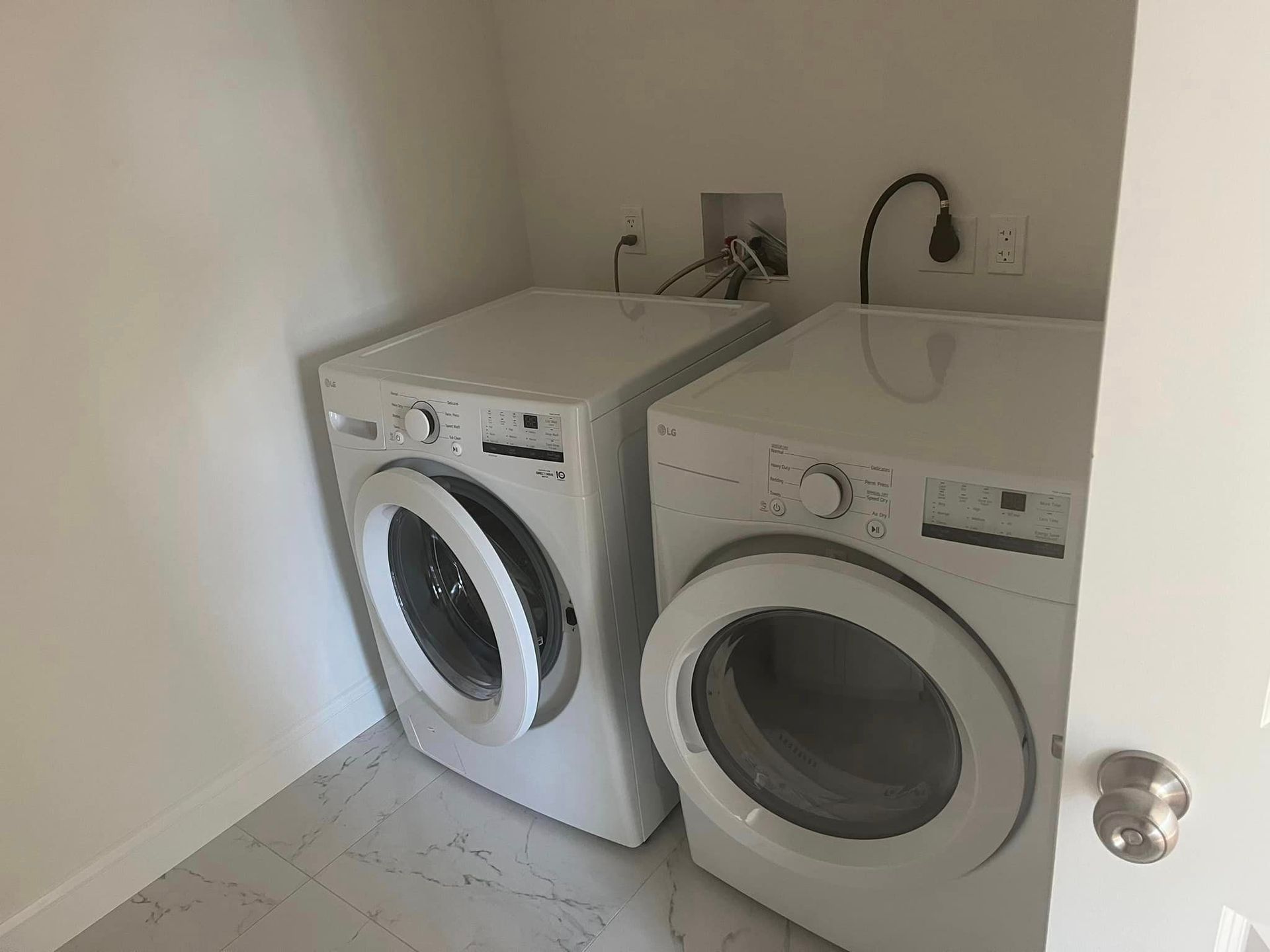 Two white washers and dryers are in a laundry room.