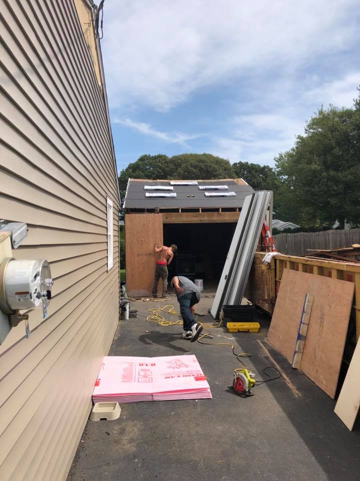 A man is kneeling down in front of a garage that is being built