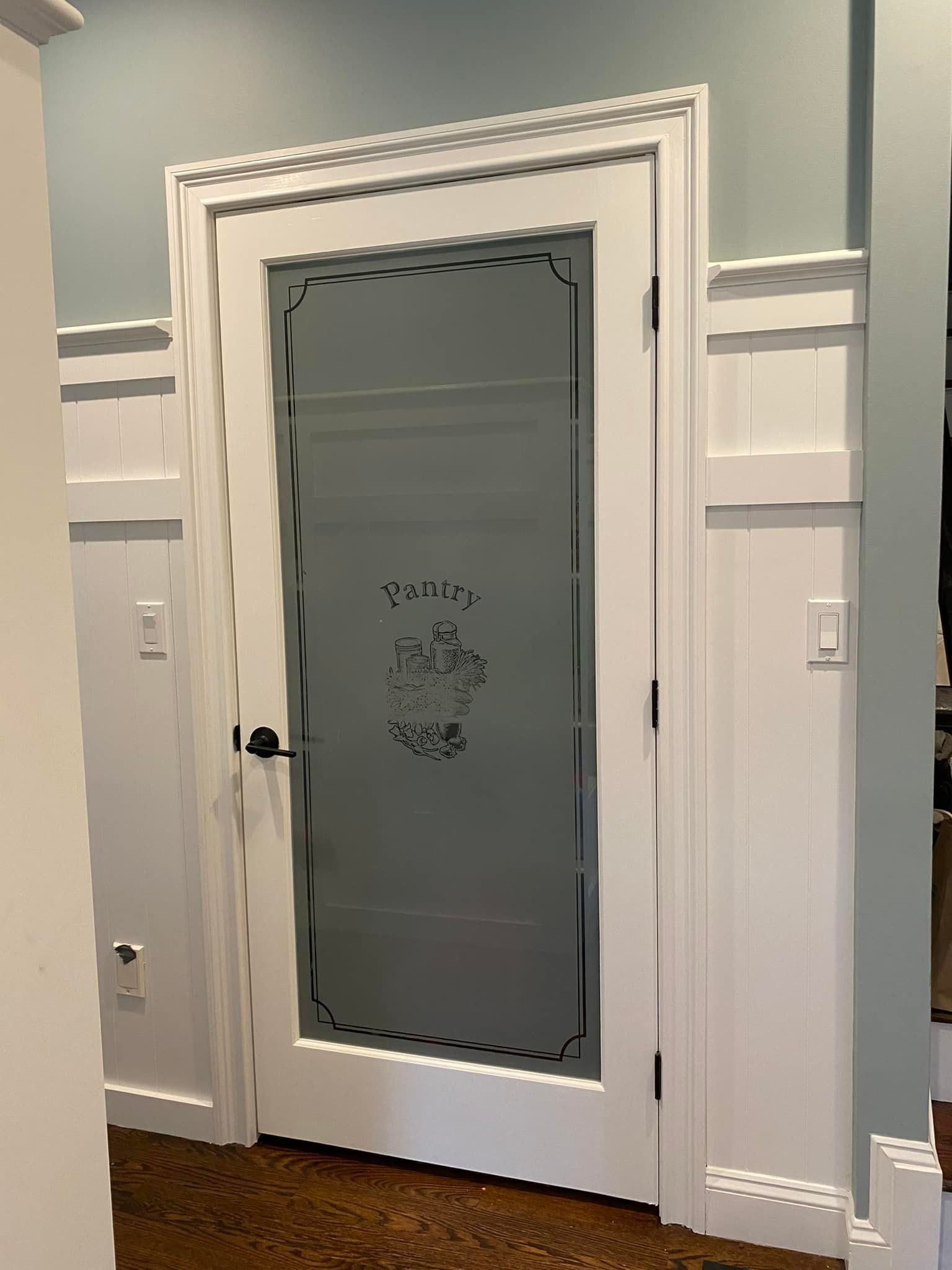 A white door with a stained glass window in a hallway.