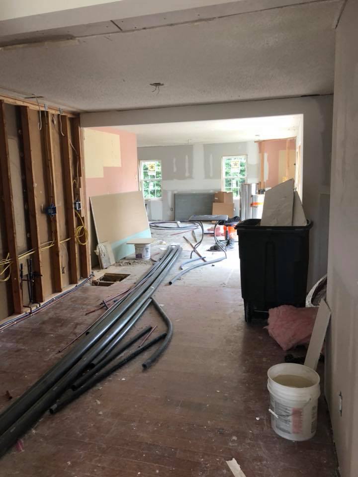 A room under construction with a bucket of water on the floor.