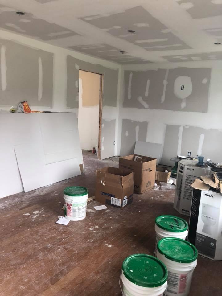 A room with buckets of paint and boxes on the floor.