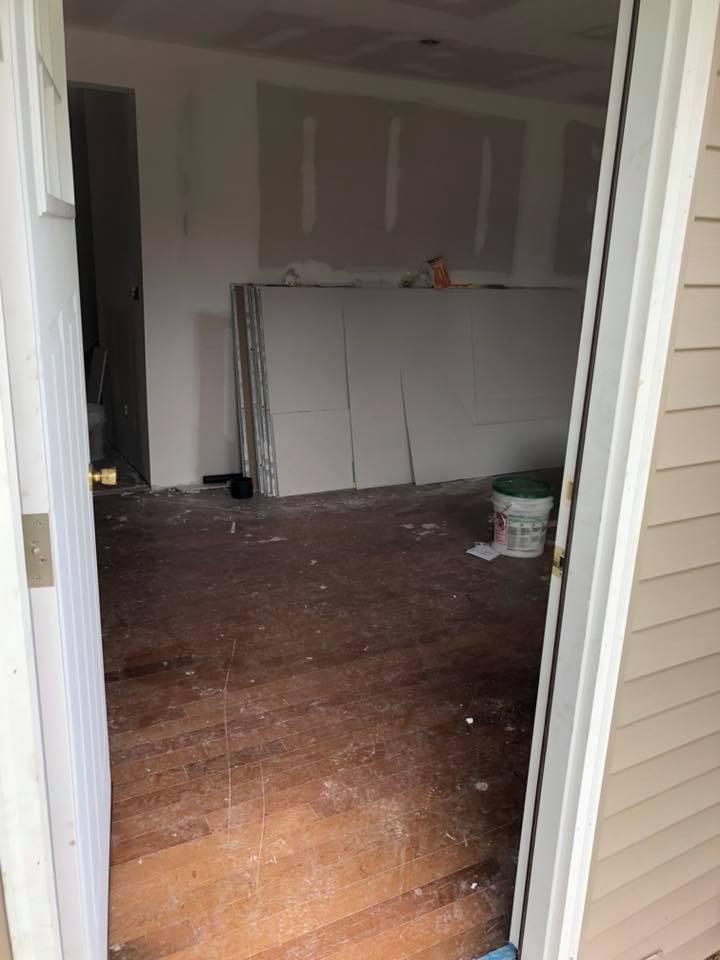 A room with a wooden floor and white walls is being remodeled.