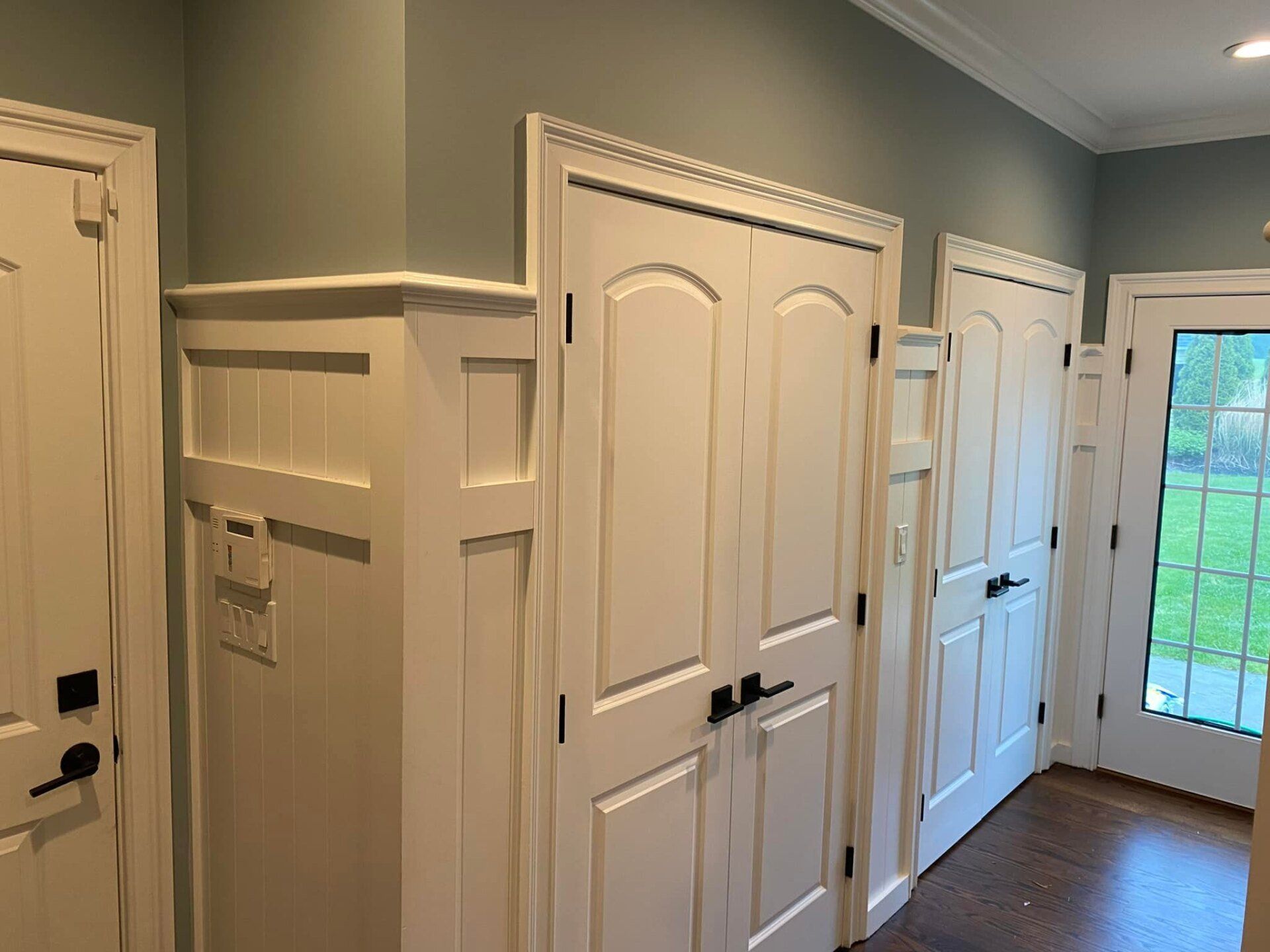 A hallway with lots of white doors and a sliding glass door.