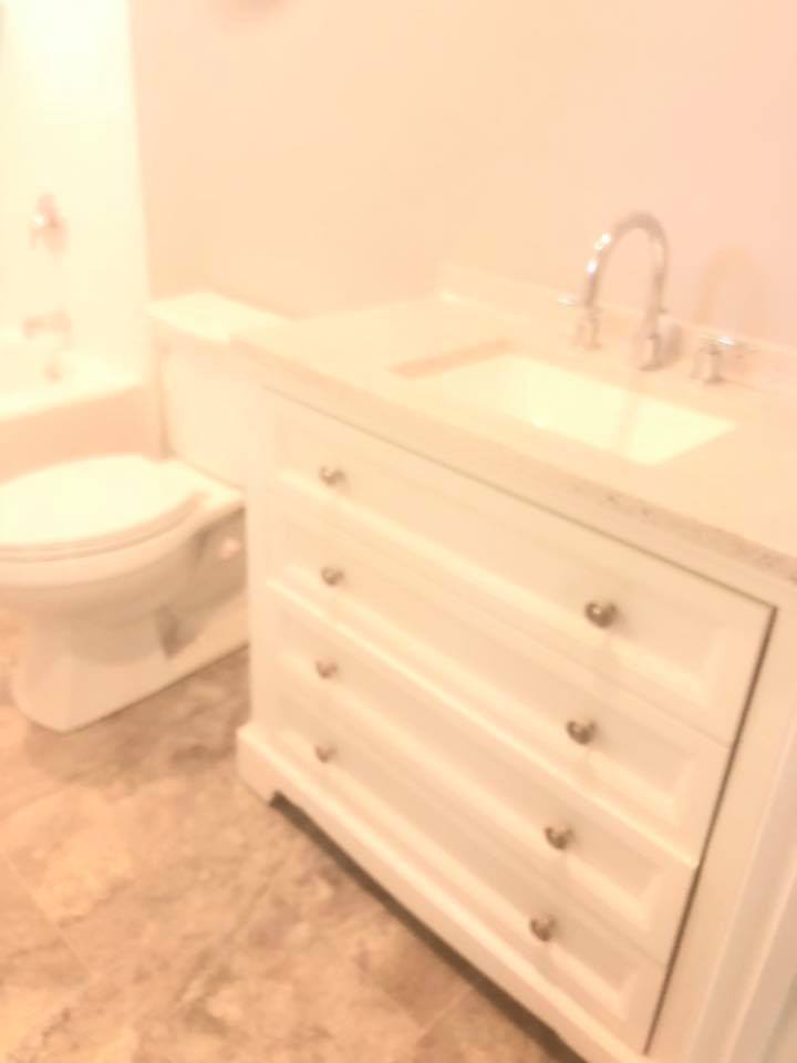 A bathroom with a toilet a sink and a dresser