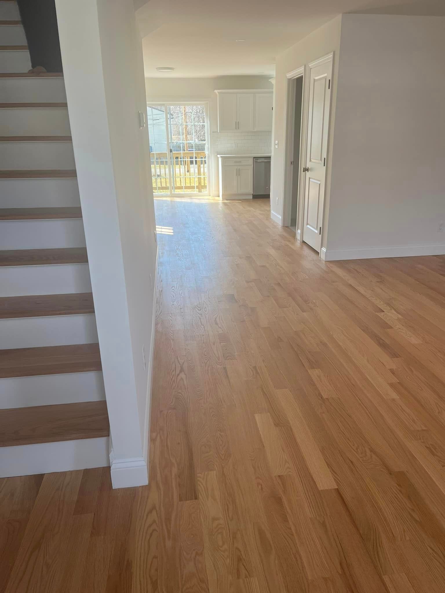 An empty house with hardwood floors and white walls.