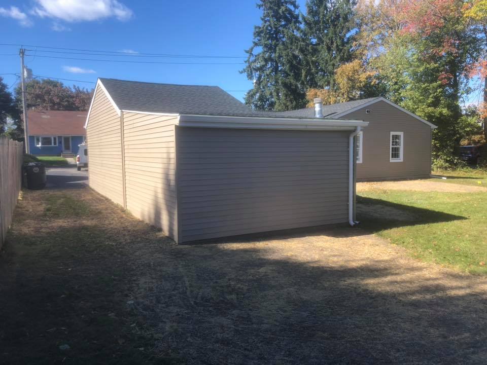 There is a garage in the backyard of a house.