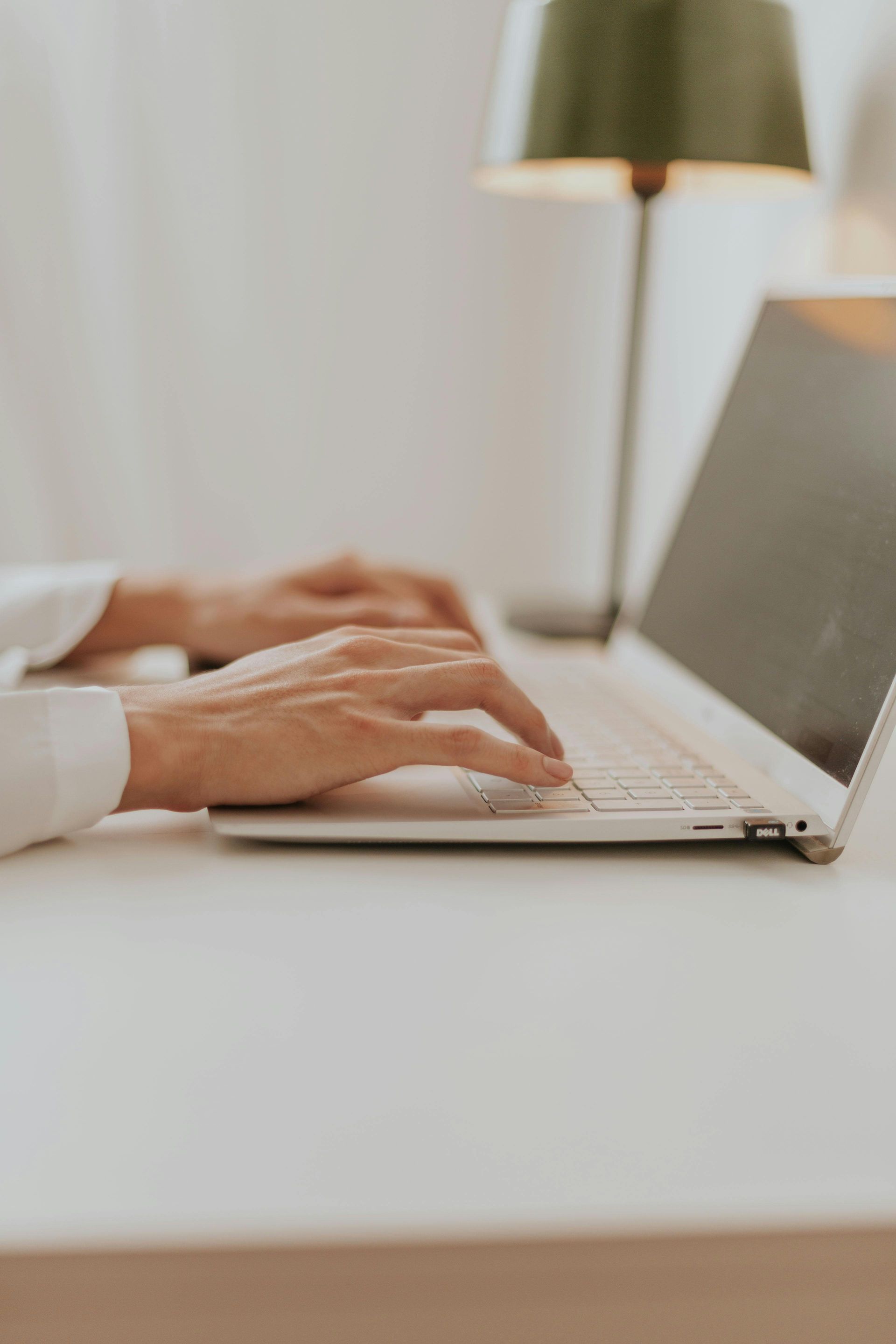 A person is typing on a laptop computer at a desk.