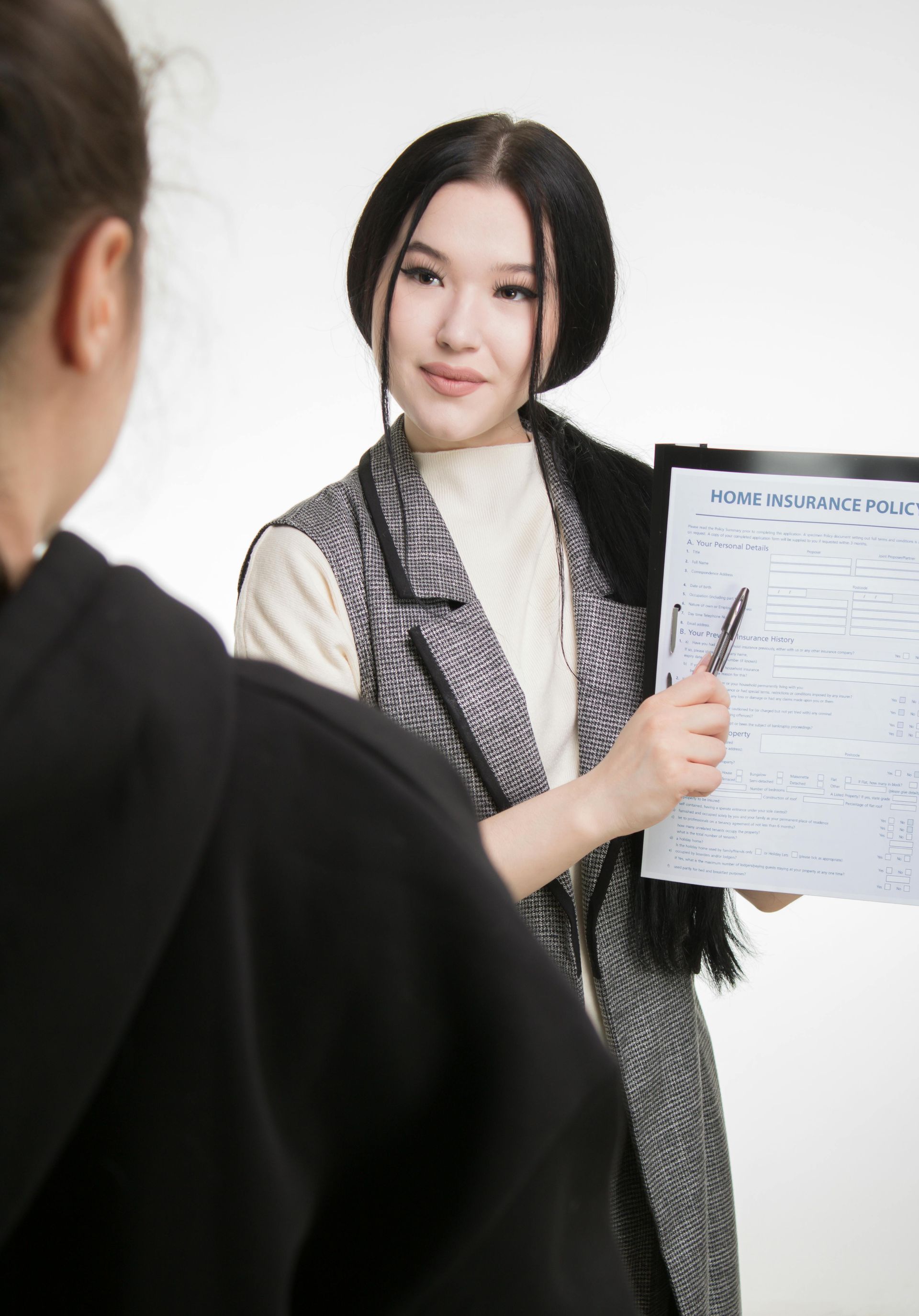 A woman is holding a piece of paper and talking to another woman.