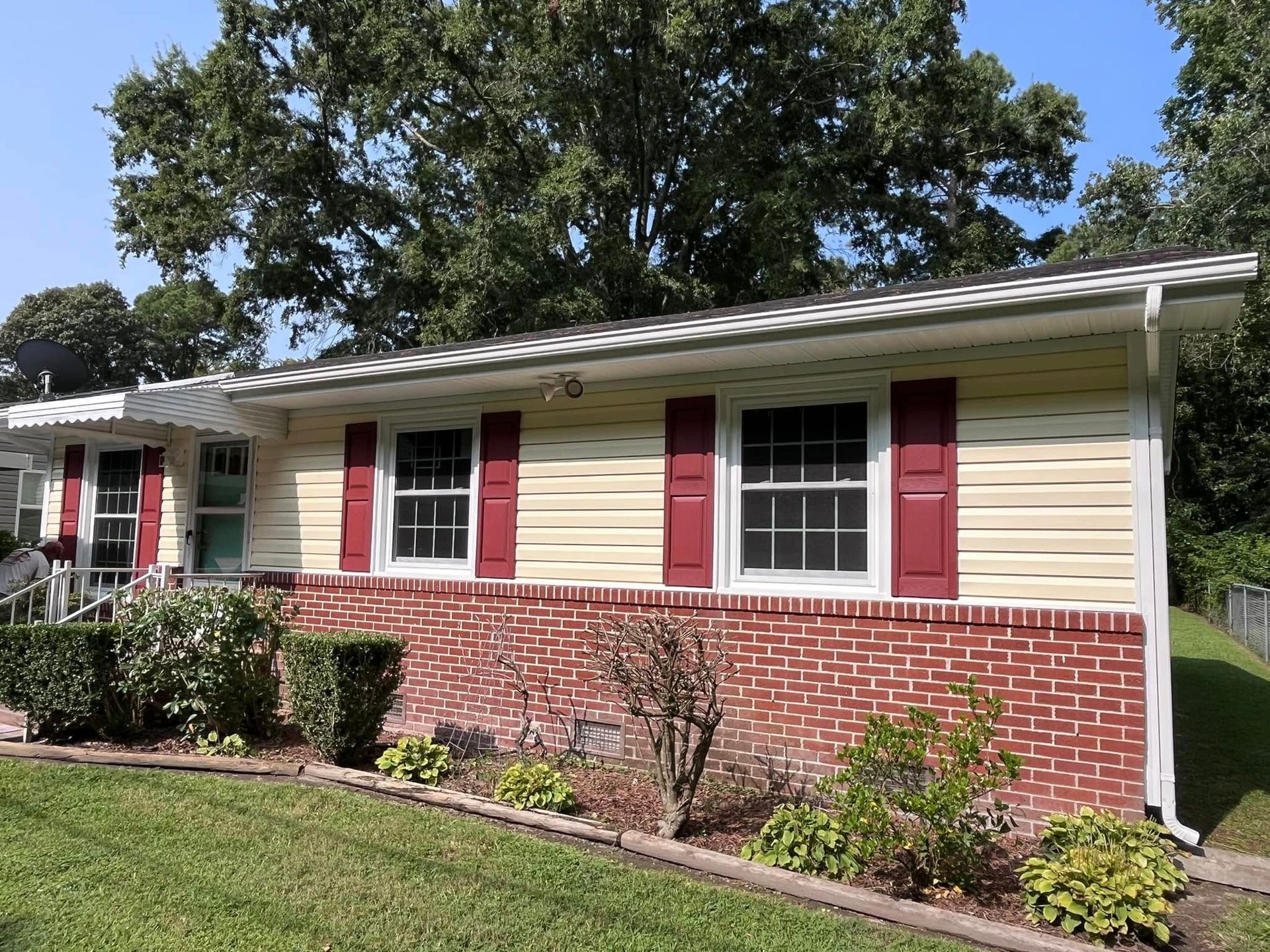 A house with red shutters on the windows and a brick wall