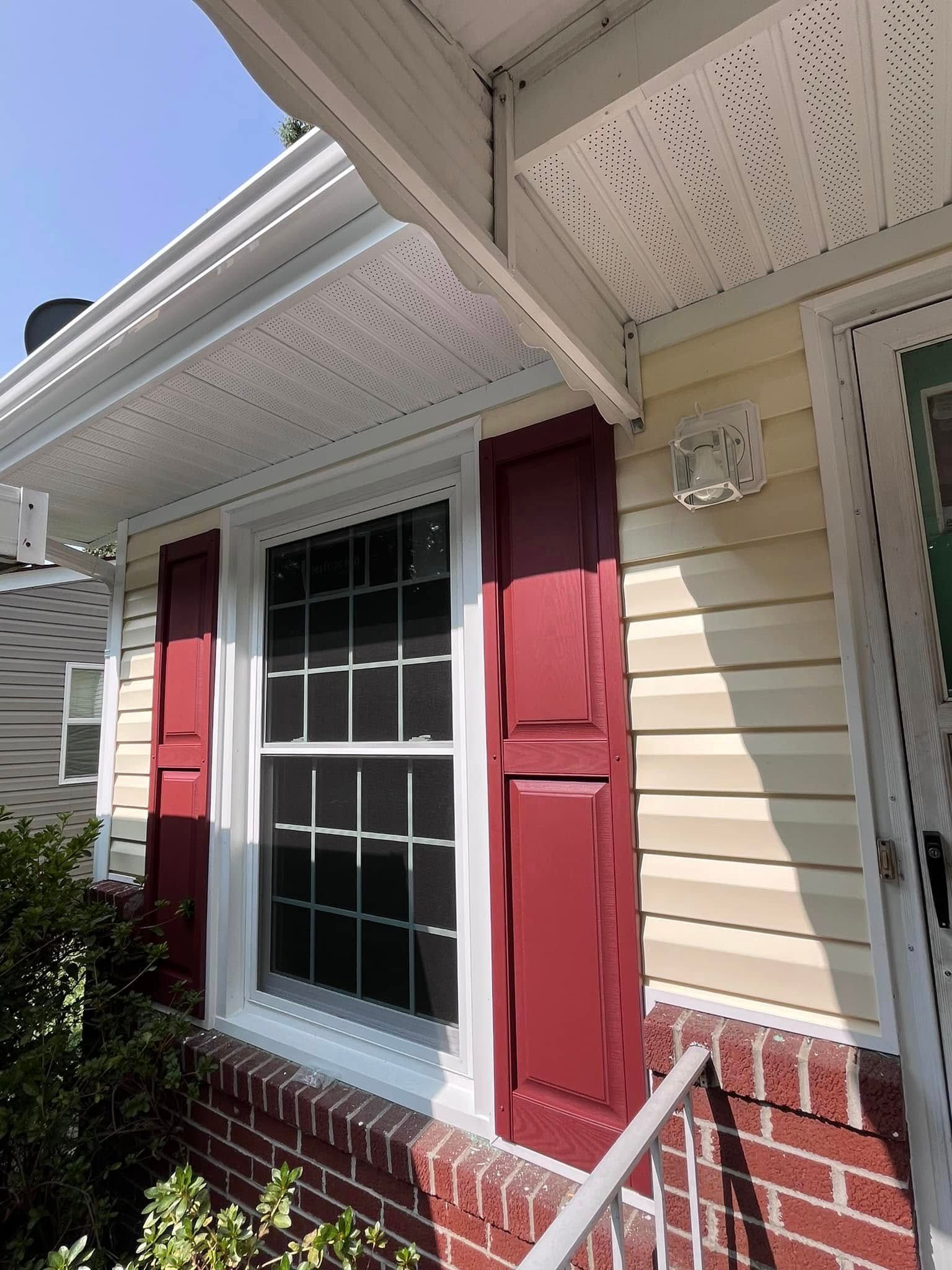 The front of a house with red shutters and a window.