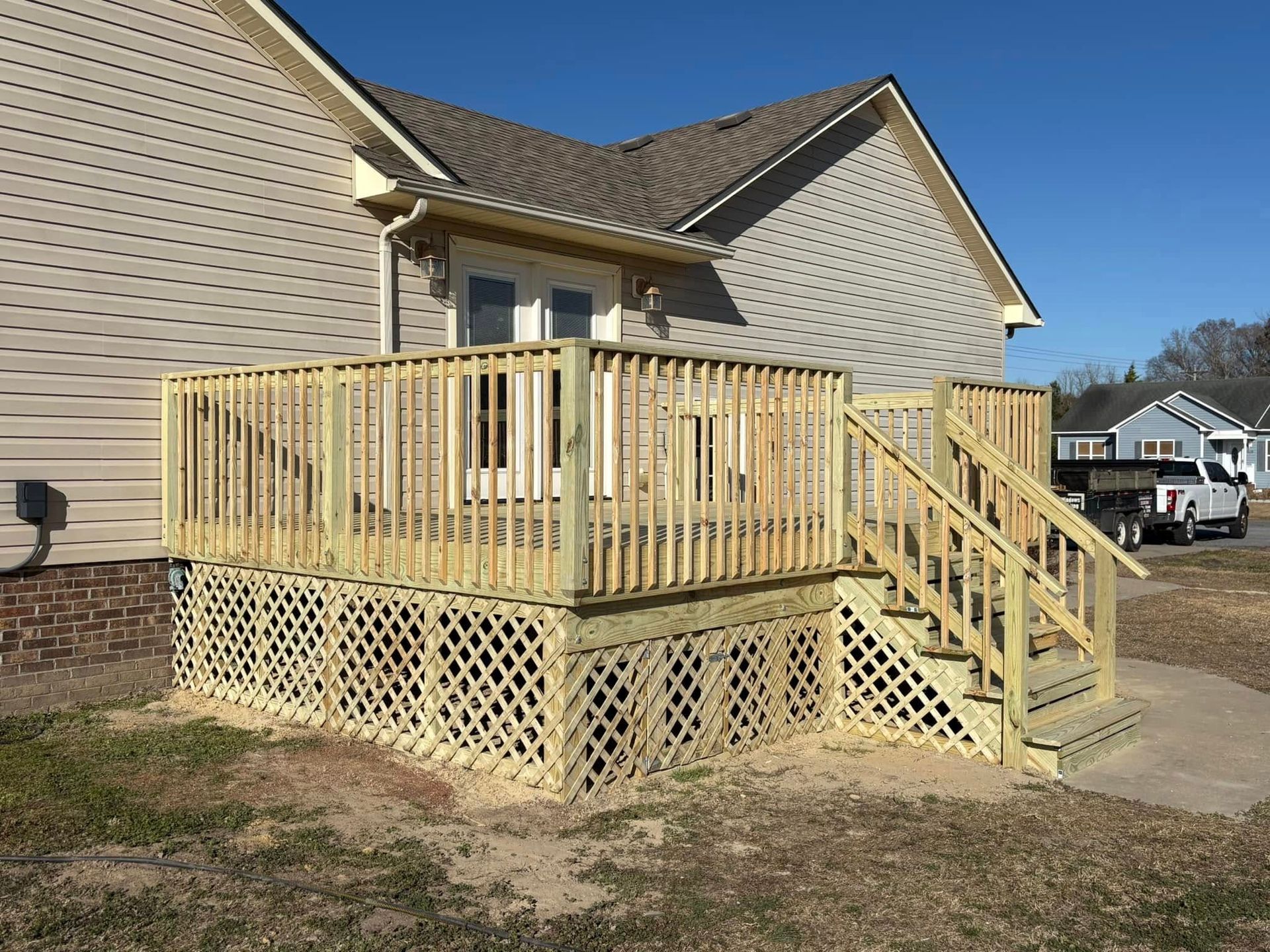 A wooden deck with stairs is in front of a house.