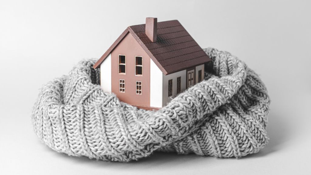 A small house is wrapped in a knitted scarf.