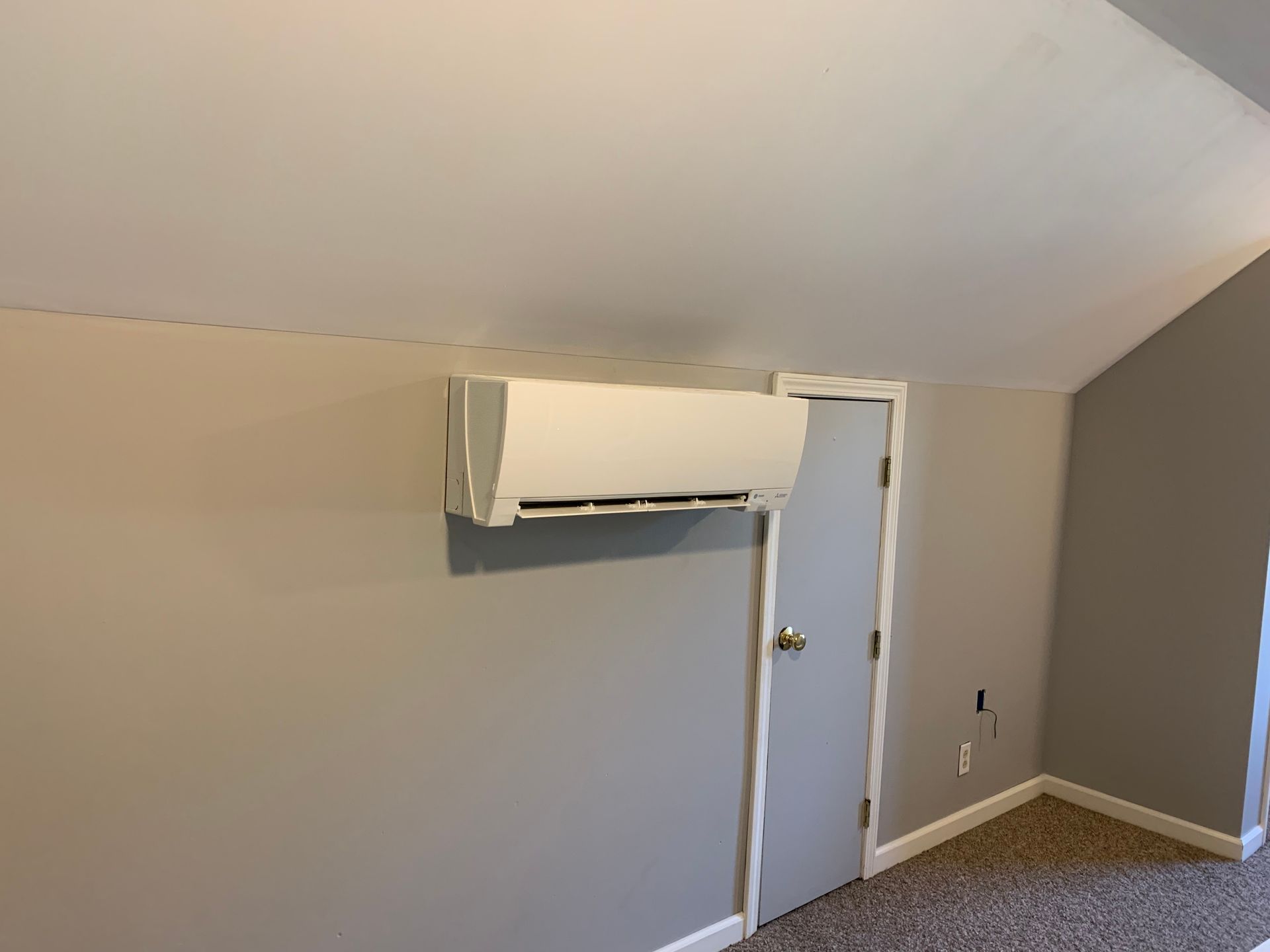 A room with a door and a wall mounted air conditioner.