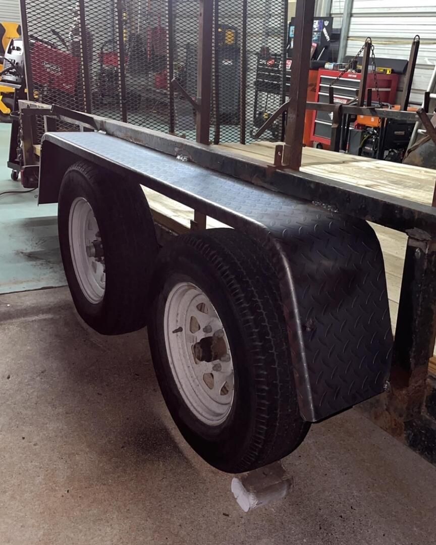 a black trailer with white wheels is parked in a garage