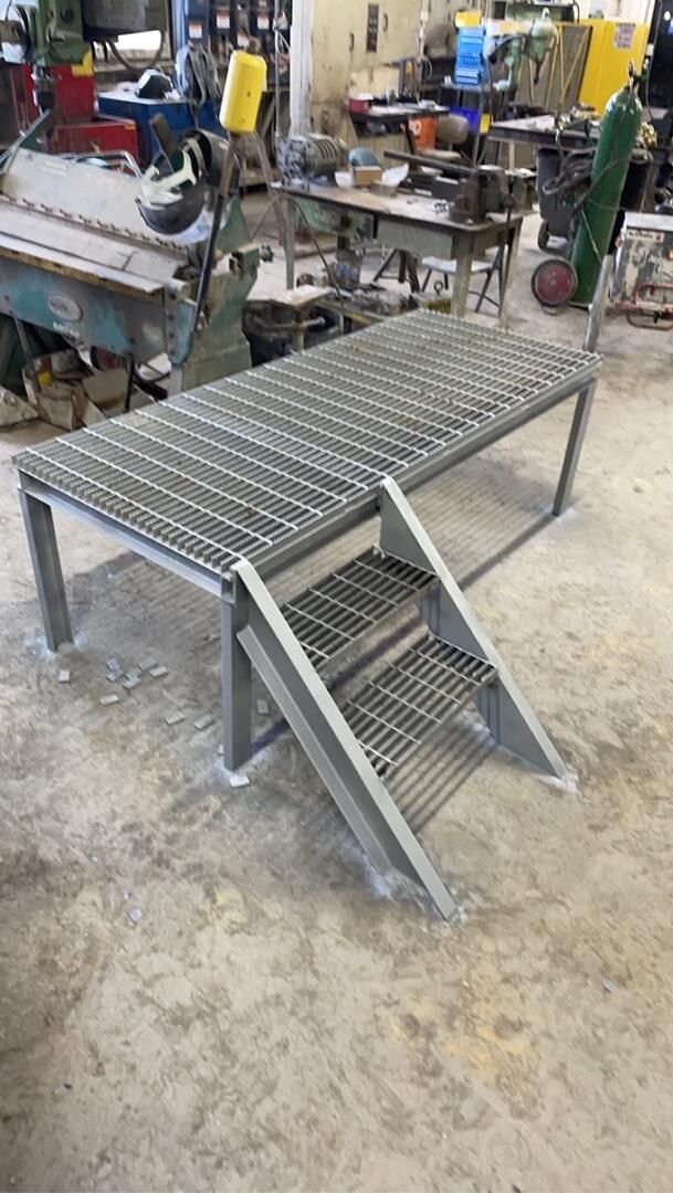 a metal platform with stairs attached to it in a factory .