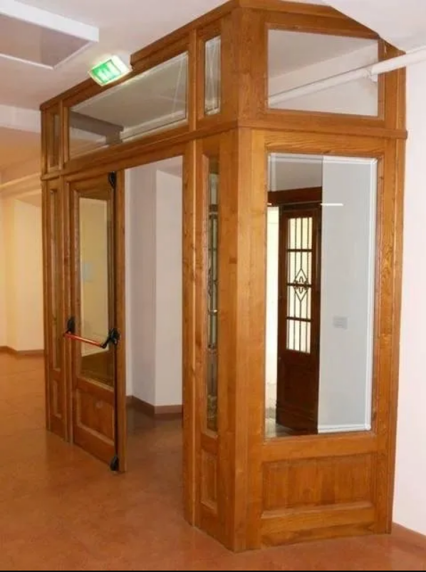 Ingresso in legno con porte in vetro, corridoio e segnale di uscita.