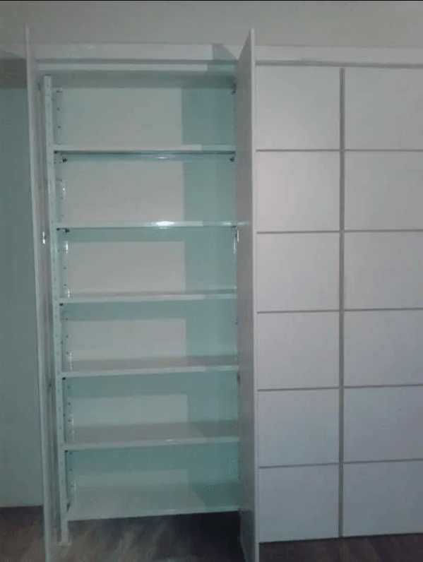 Libreria bianca con ripiani aperti a sinistra e ante chiuse a destra.