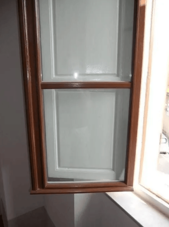 Finestra con cornice in legno, pannello bianco, aperta. Luce che entra da destra.