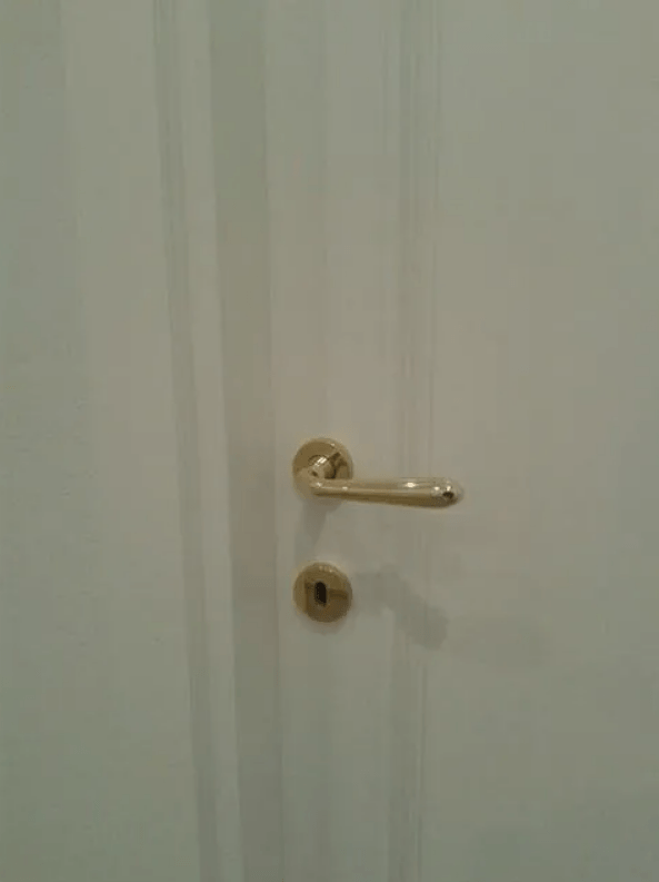 Porta bianca con maniglia e serratura dorate.