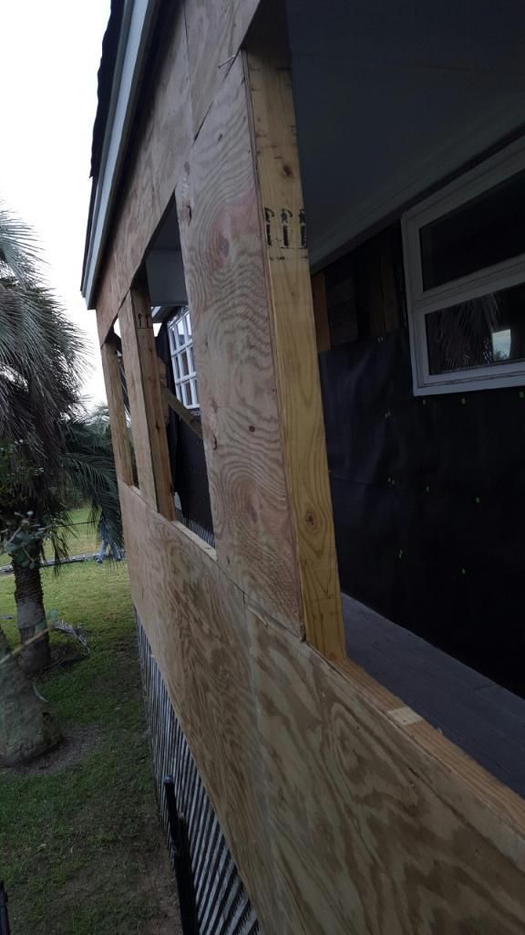 A house is being remodeled with plywood covering the windows.