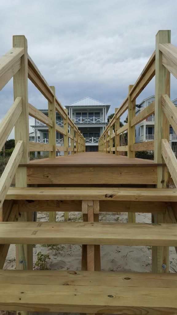 A wooden walkway leading to a house on the beach.
