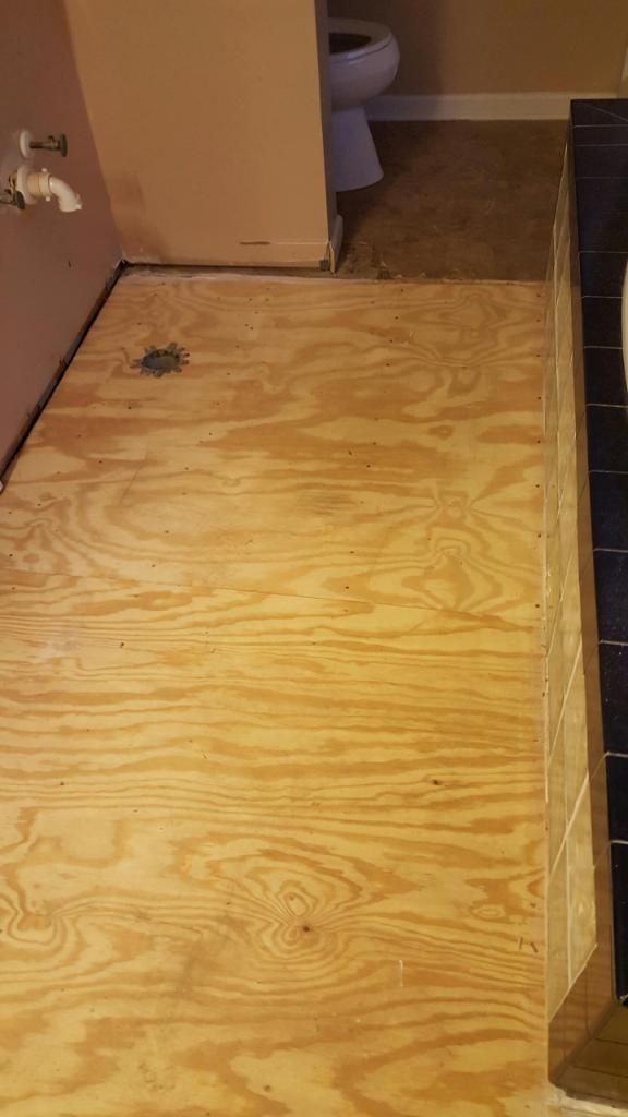 A bathroom with a wooden floor and a toilet.