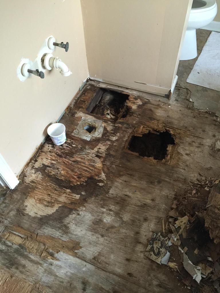 A bathroom with a hole in the floor and a toilet.