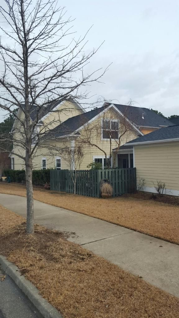 A house with a fence and a tree in front of it.